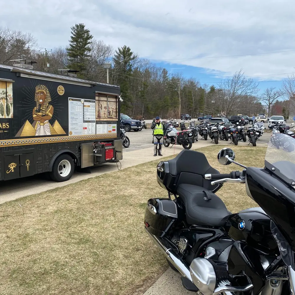 The Wraps & Kebabs truck's pyramid mural and menu board, parked among dozens of motorcycles at a rally