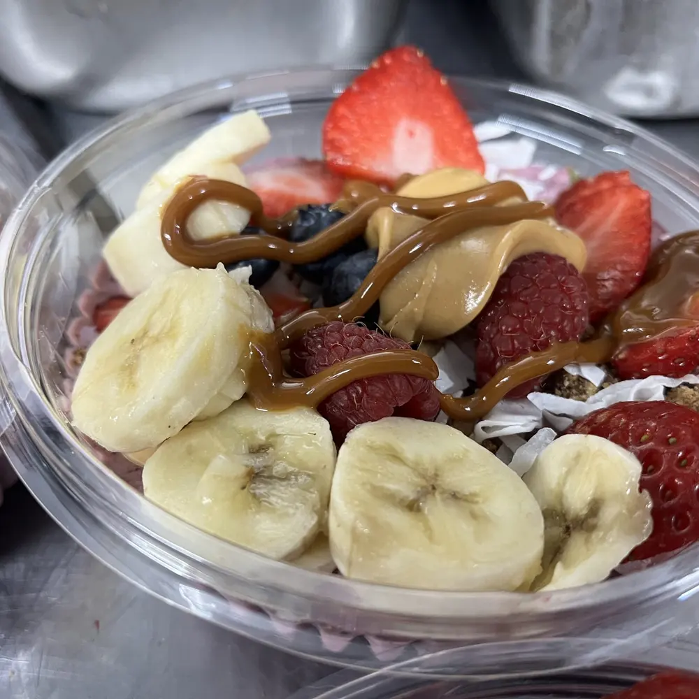 A parfait cup with banana, strawberries, granola and a caramel drizzle