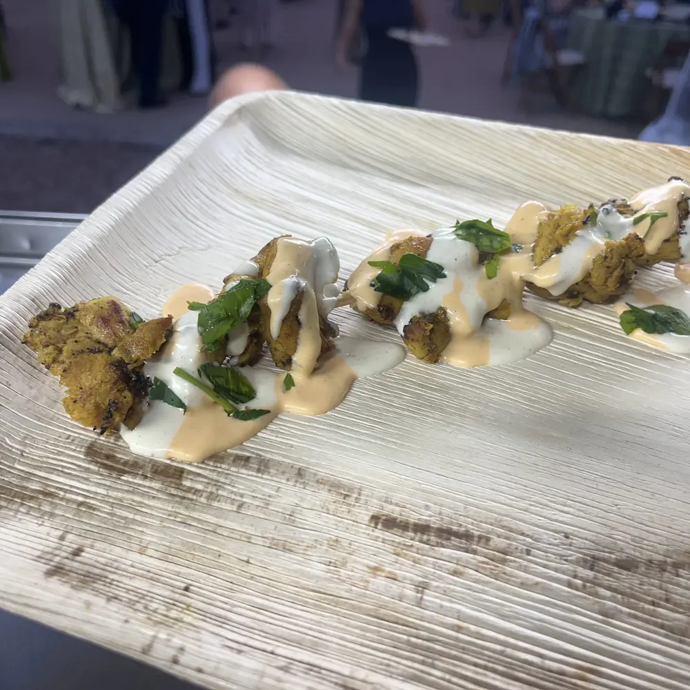 Fried bites plated with a tahini-style sauce and fresh herbs for a passed appetizer