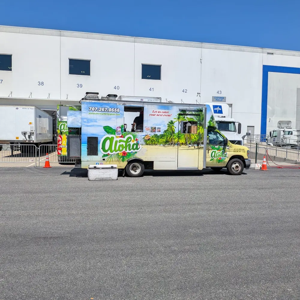 The Aloha truck parked at a corporate loading dock beside a large white warehouse