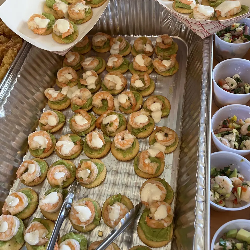A tray of seafood canapes on crisps, ready for a catered event