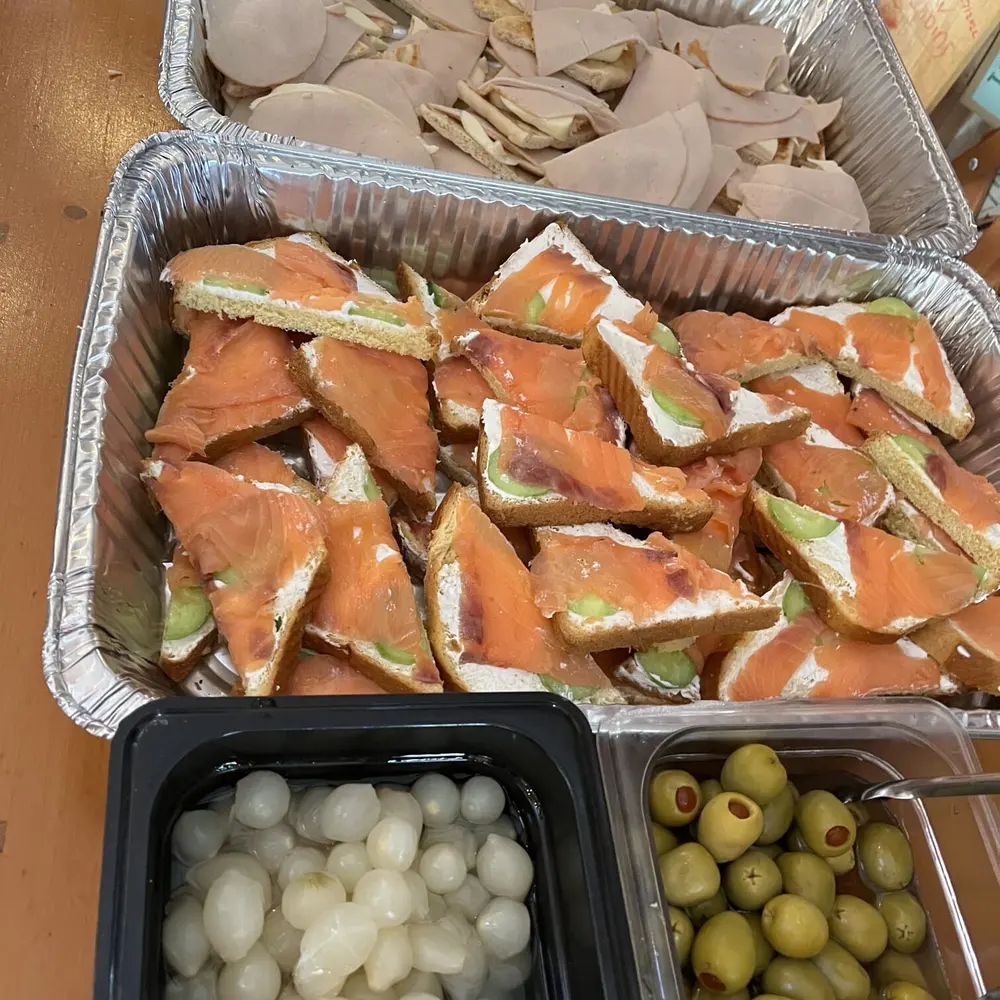 A catering tray of smoked salmon canapes alongside pearl onions and olives