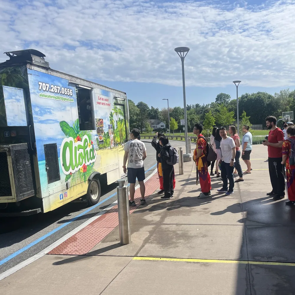 A line of students in red uniforms waiting at the Aloha truck's window