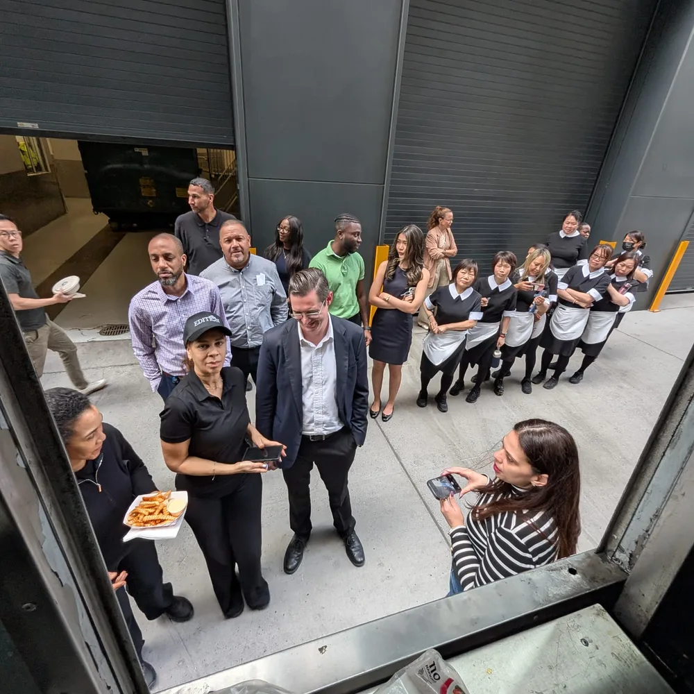 Guests and housekeeping staff in black-and-white uniforms lined up outside, seen from the truck's service window